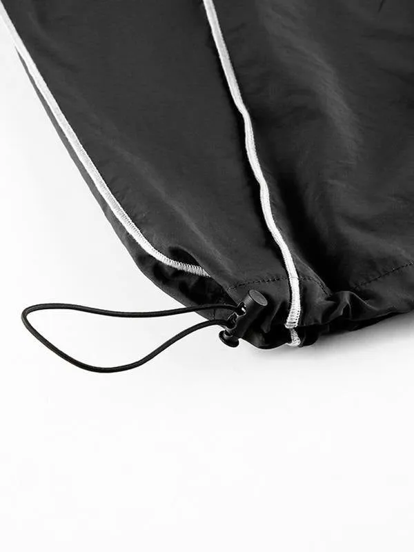 Black parachute trousers with cargo pockets and piping details