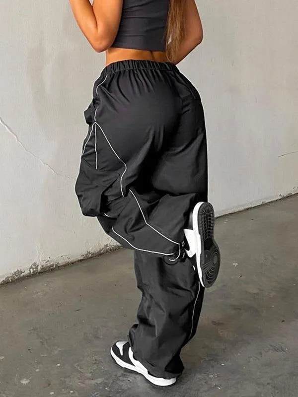 Black parachute trousers with cargo pockets and piping details