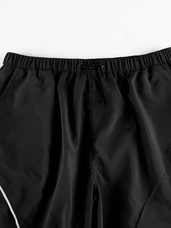 Black parachute trousers with cargo pockets and piping details